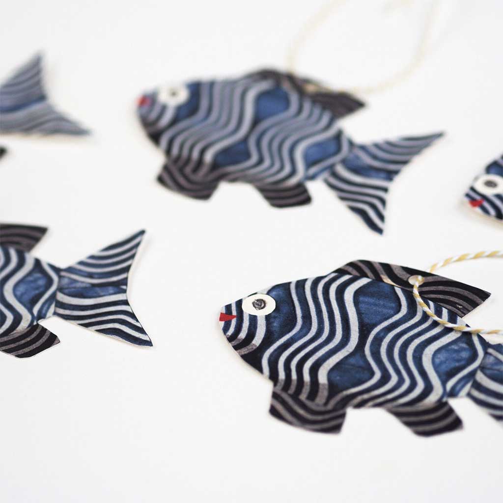 Set of five fish-shaped gift tags with colorful twine on white background