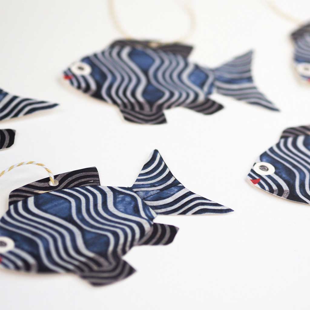 Set of five fish-shaped gift tags with colorful twine on white background