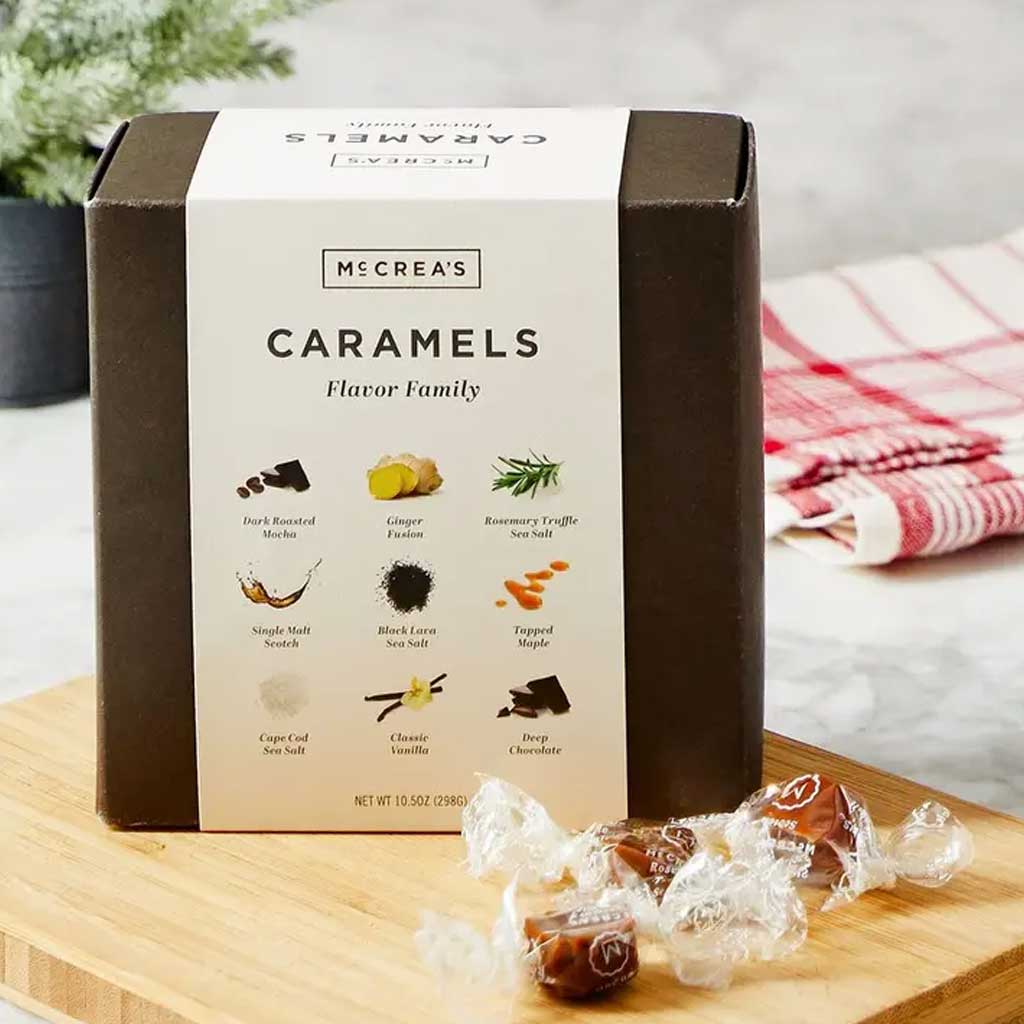 Box of McCrea's Caramels on a wooden board with caramels around it.