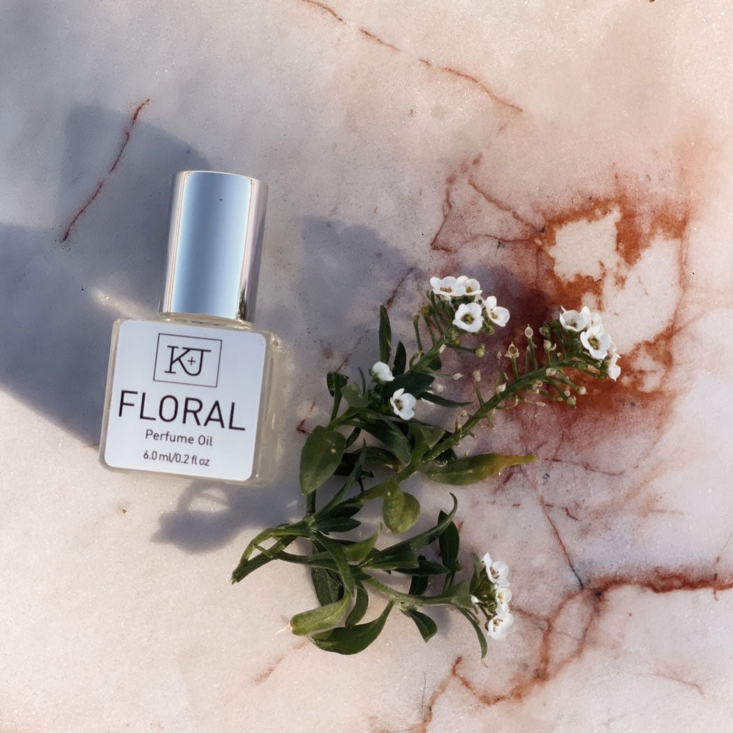 Floral perfume oil bottle with flowers on a marble surface