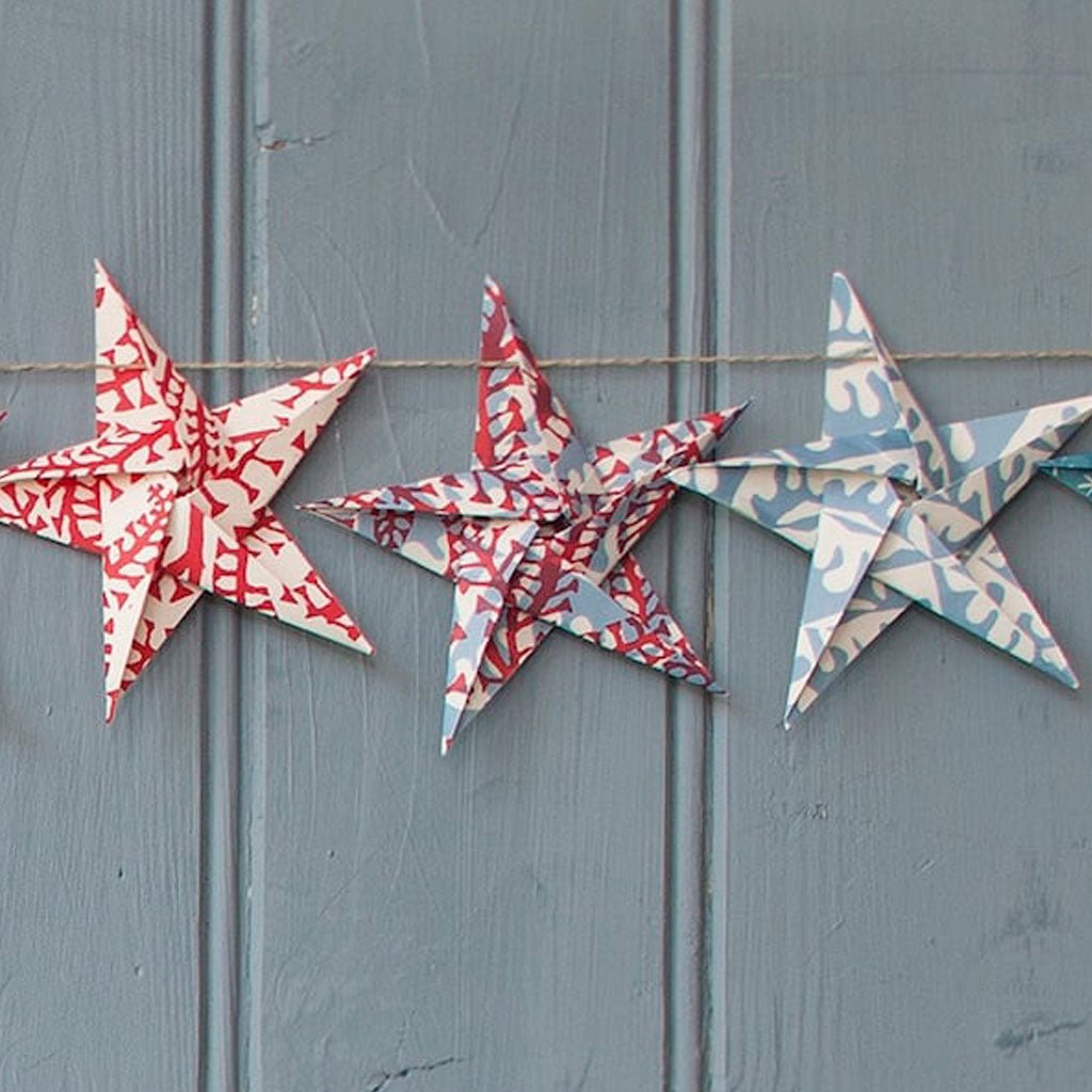 Decorative paper origami stars in red, white, and blue on a wooden background