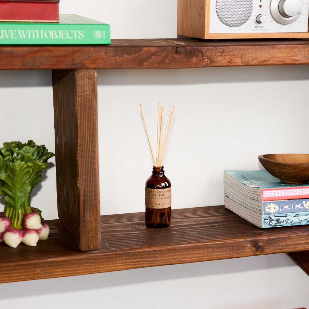 Wooden shelf with decorative items including a bottle, books, and a plant.