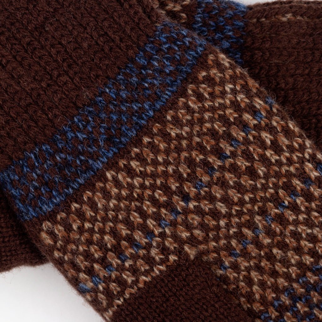 Close-up of a brown knit textile with a blue patterned band and a woven brown-and-beige geometric section.