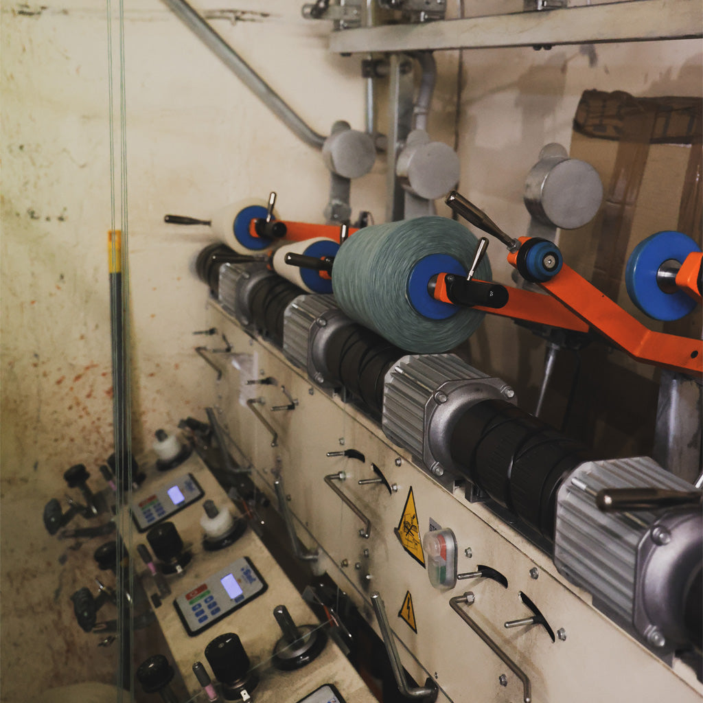 Textile spinning machine with a cone of blue yarn.