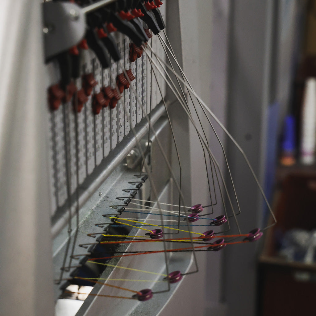 An industrial knitting machine with multiple colored yarns.