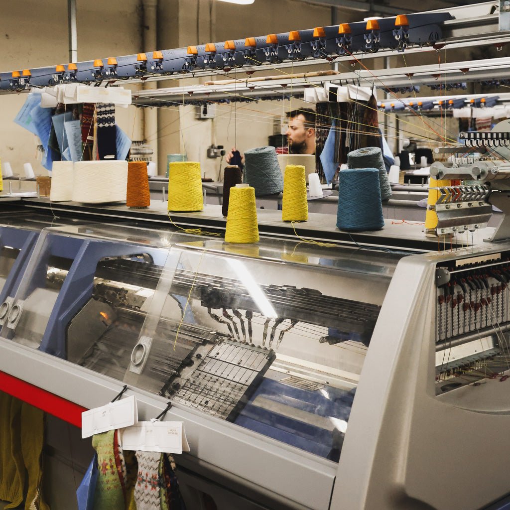 A large industrial knitting machine with various cones of yarn.