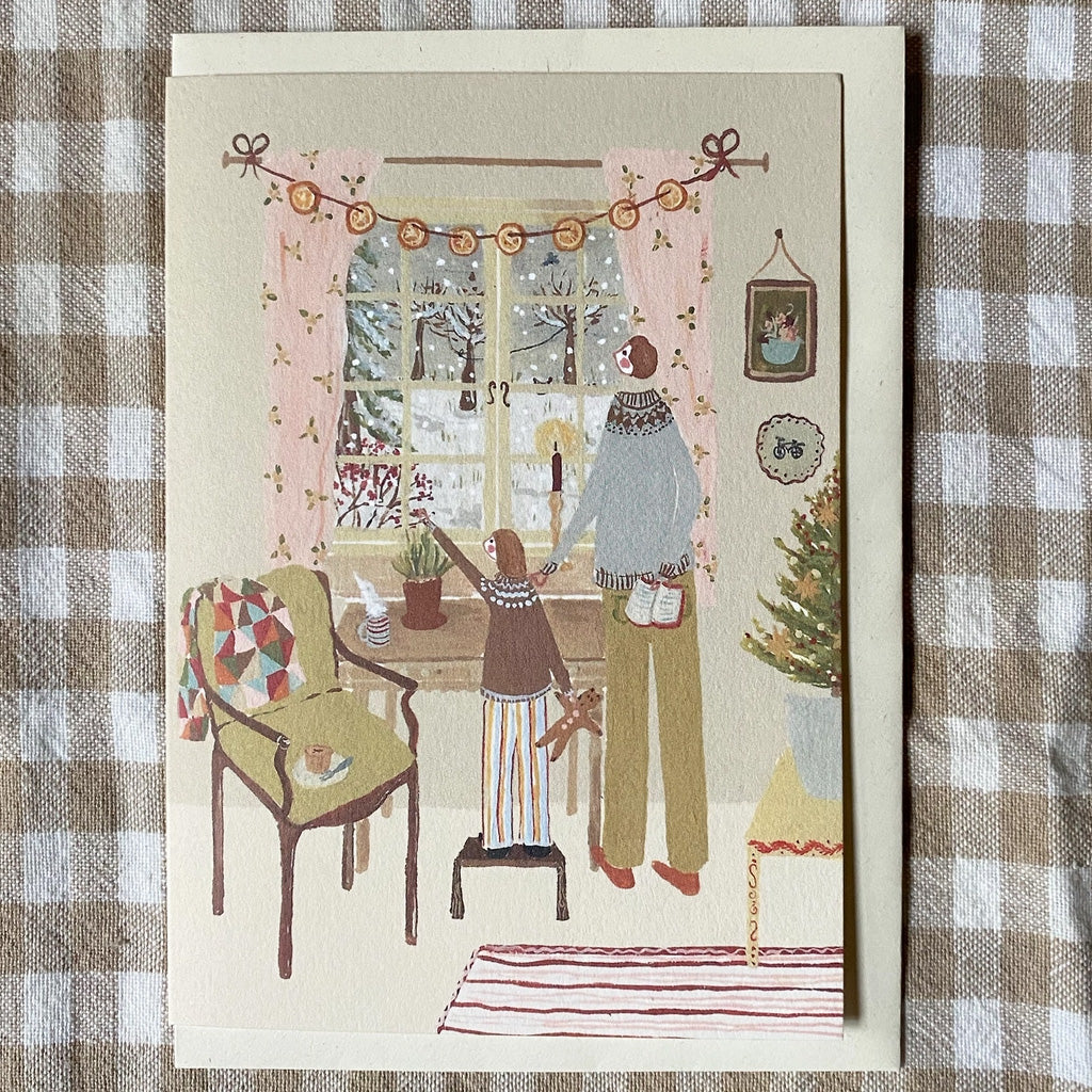 A holiday card with illustration laying on gingham fabric.