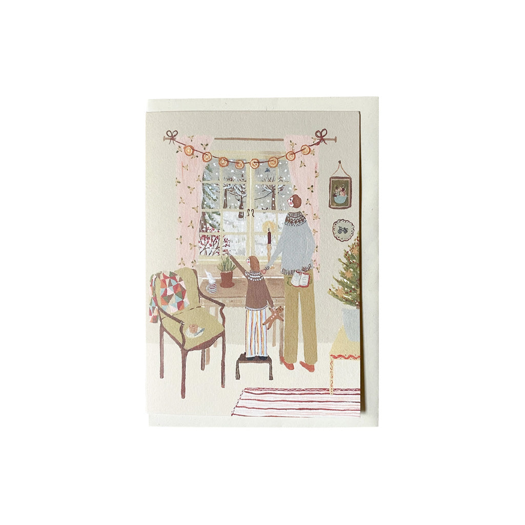 Holiday card with living room illustration and envelope on white background.