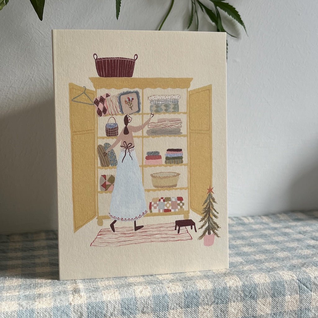 Holiday card standing upright on blue gingham fabric.