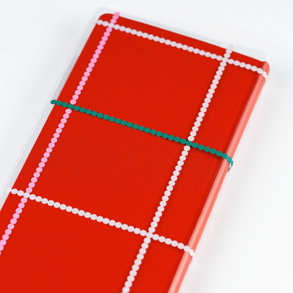 Clear Hobonichi Weeks clear cover with colorful dotted plaid pattern on red Weeks planner