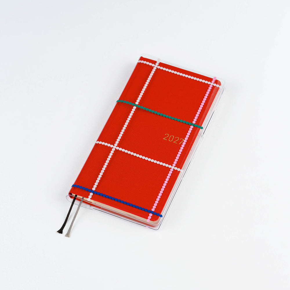 Clear Hobonichi Weeks clear cover with colorful dotted plaid pattern on red Weeks planner against white background