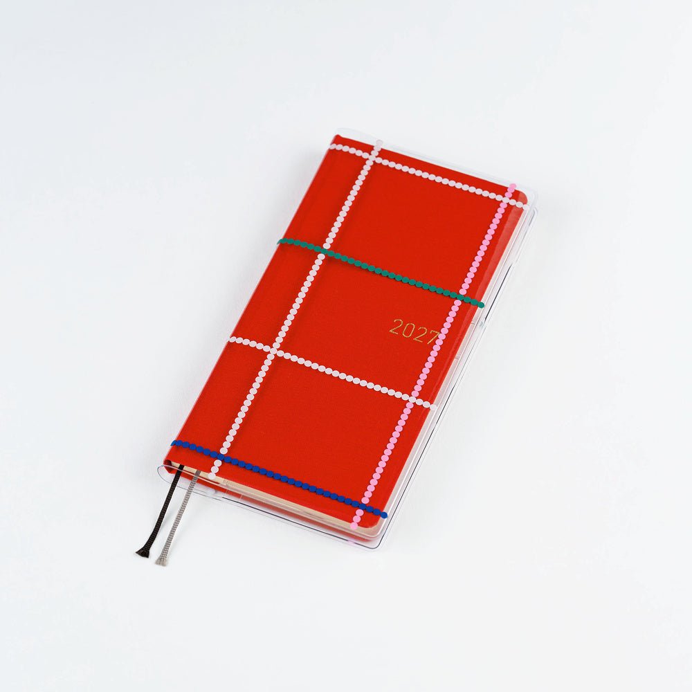 Clear Hobonichi Weeks clear cover with colorful dotted plaid pattern on red Weeks planner against white background