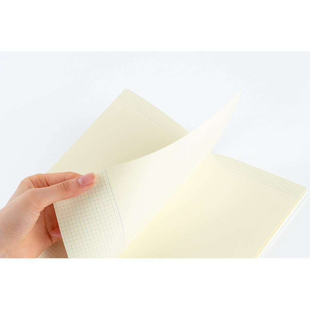 A hand holding an open notebook with cream-colored graph paper pages against a clean white background.