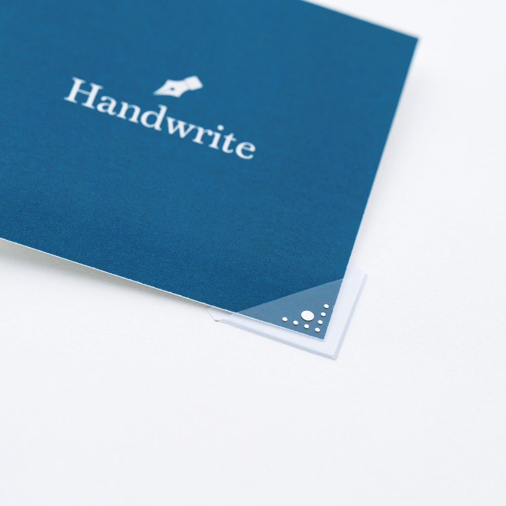 A close-up of a blue card with the word 'Handwrite' printed in white with a clear corner sticker on the page, on a white background.
