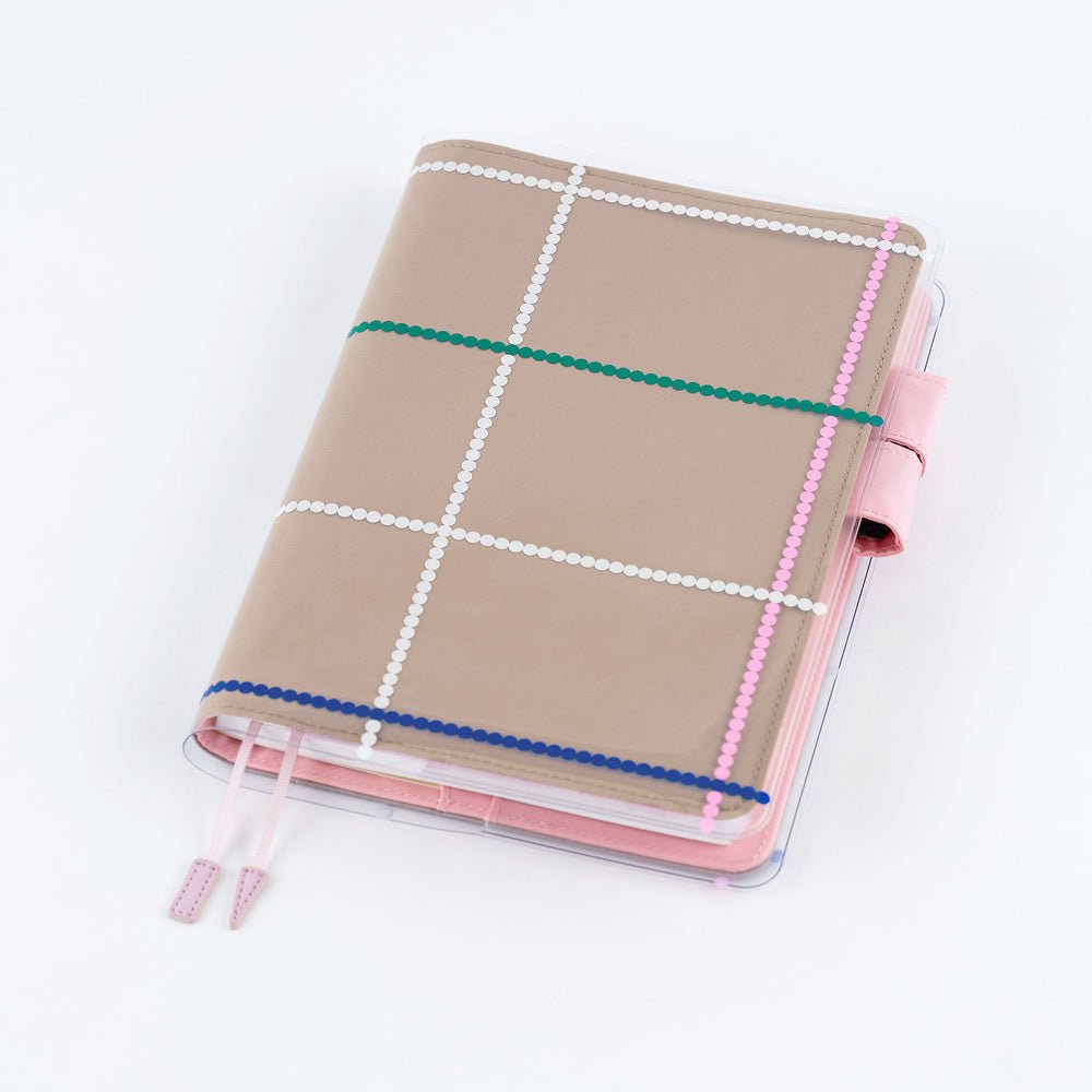 Clear cover on top of beige A5 Hobonichi Techo cover with colorful dotted plaid pattern against white background