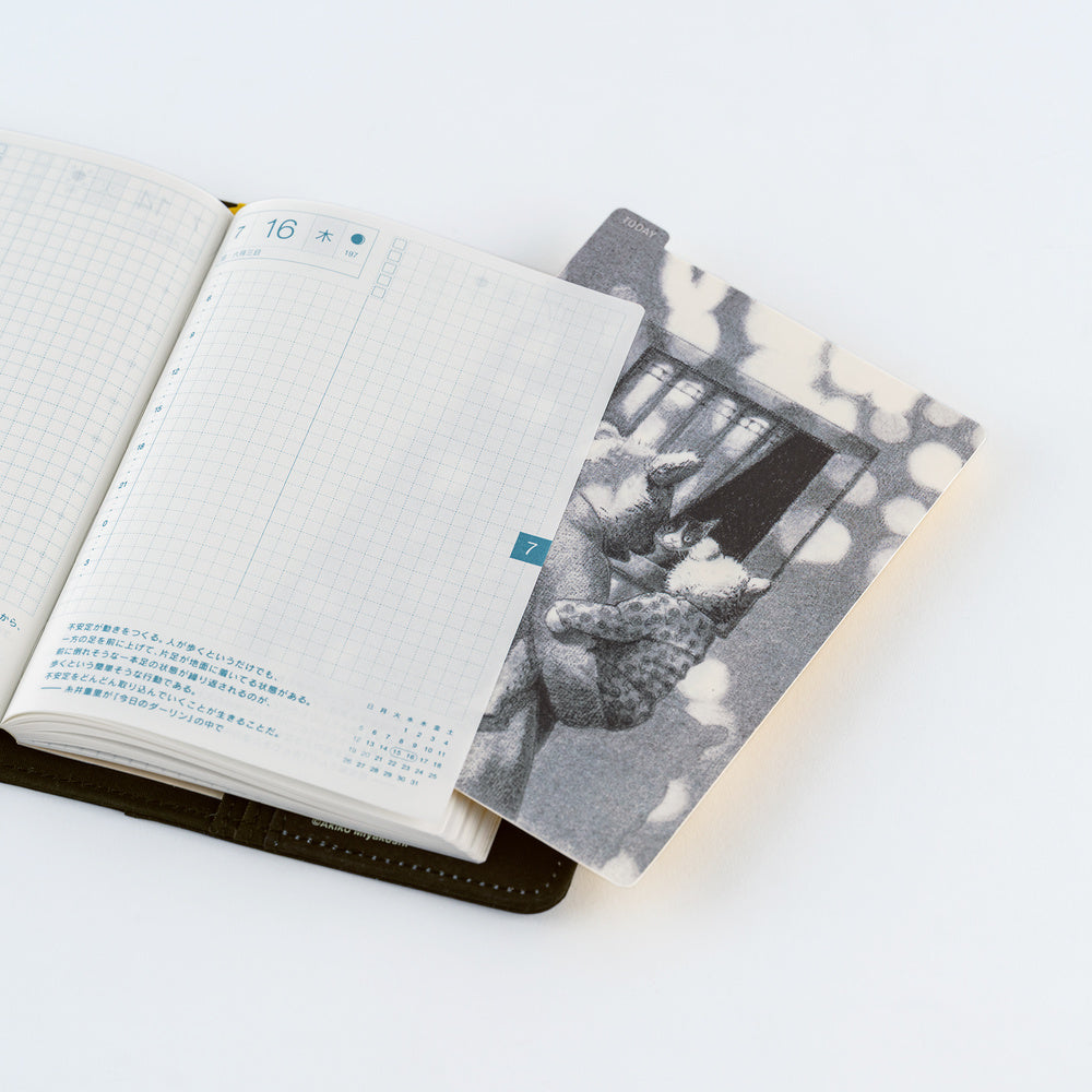 An open planner with blank grid pages on the left and a pencil board on the right, photographed on a clean white background.