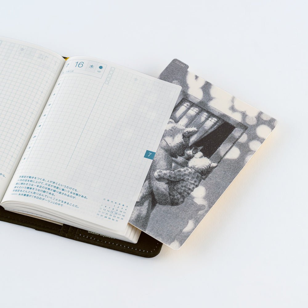 An open planner with blank grid pages on the left and a pencil board on the right, photographed on a clean white background.