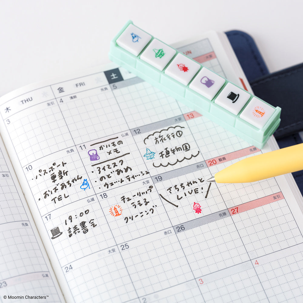 Calendar with Moomin character stamps and a yellow pen on a white background