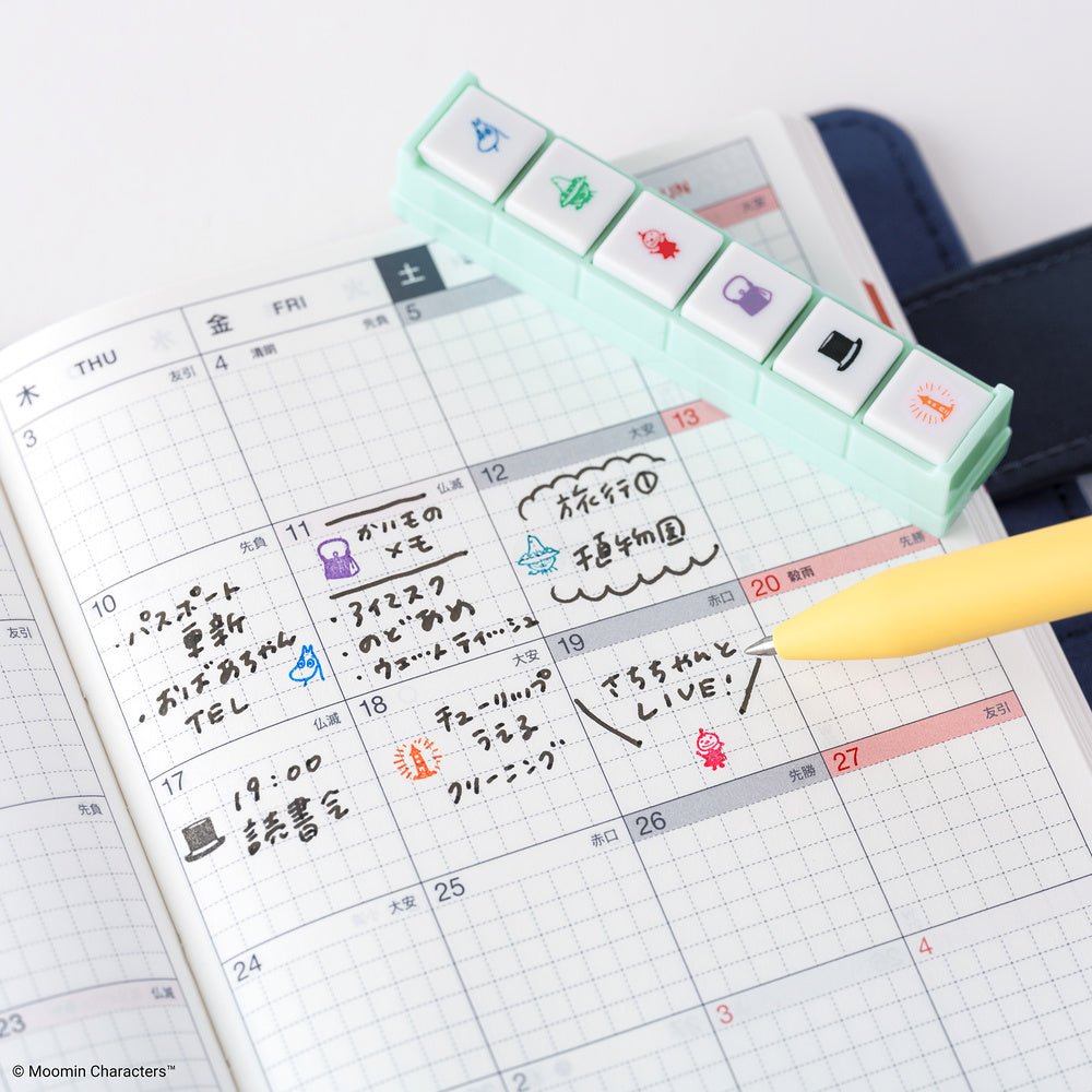 Calendar with Moomin character stamps and a yellow pen on a white background