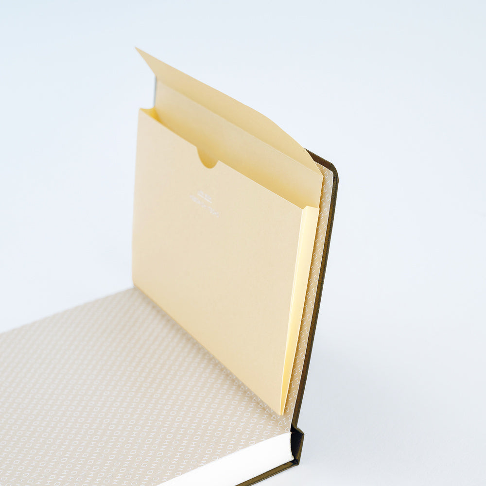 A close-up of cream pocket notebook folder open and adhered to a planner on white background