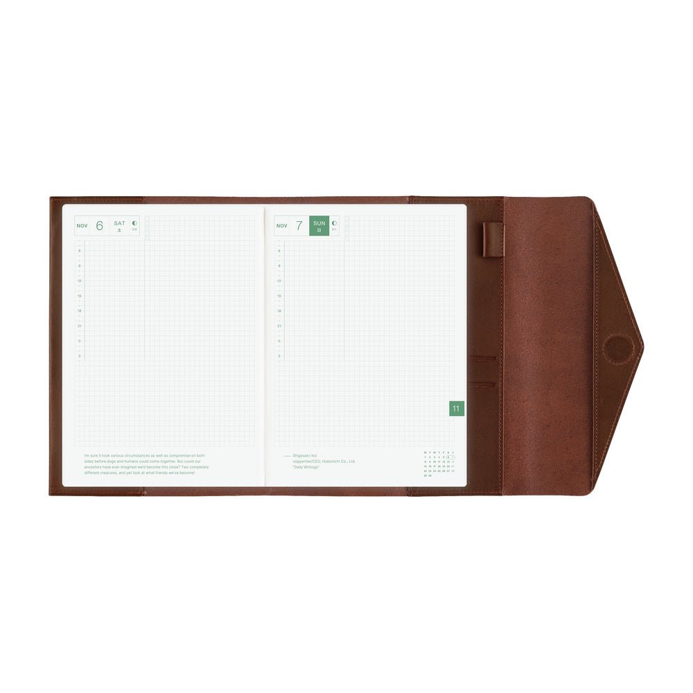 An open brown leather Hobonichi Techo cover with a white grid planner inside, shown against a plain white background.