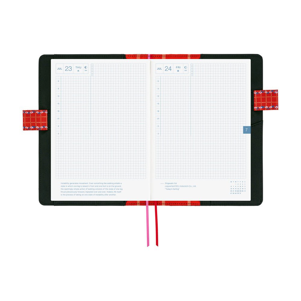 An open planner with white grid pages and a black and interior with red pen closure loops and two ribbon bookmarks hanging below, one red and one pink, on a plain white background.