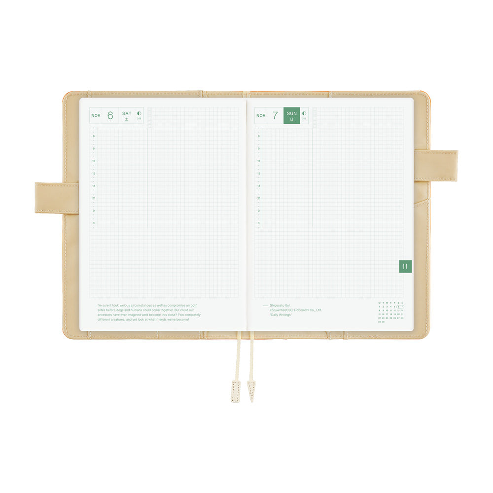 An open grid planner with white pages and an ivory interior cover, featuring ivory pen loop closures and ribbon bookmarks, shown on a solid white background.