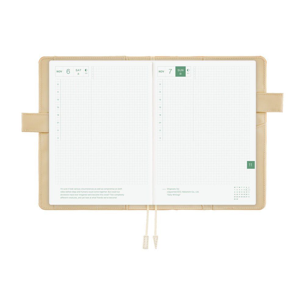 An open grid planner with white pages and an ivory interior cover, featuring ivory pen loop closures and ribbon bookmarks, shown on a solid white background.