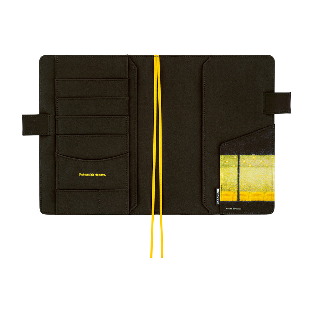 The interior of a black fabric planner cover with multiple card slots, pen closure loops, and yellow ribbon bookmarks, shown open against a white background.