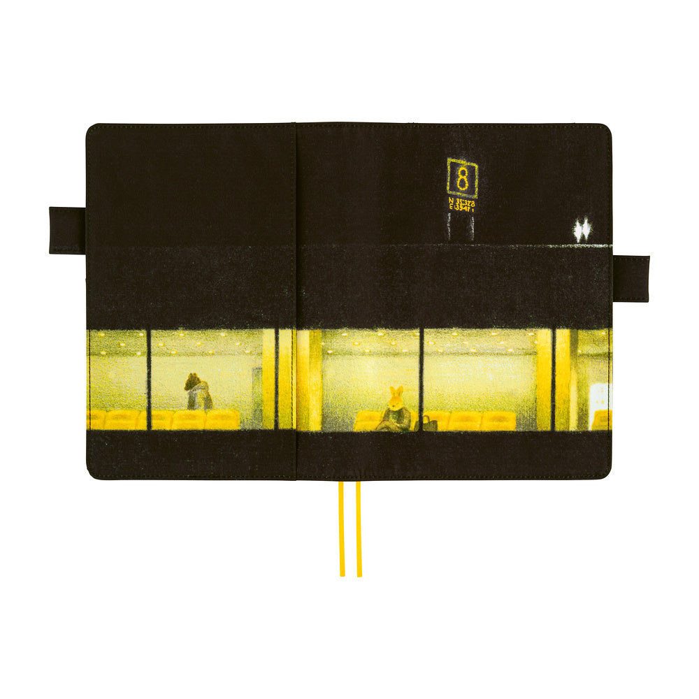 A black planner cover, featuring a printed graphic of a yellow-lit airport interior with window panes and a small yellow sign. Two yellow ribbon bookmarks extend from the bottom center.