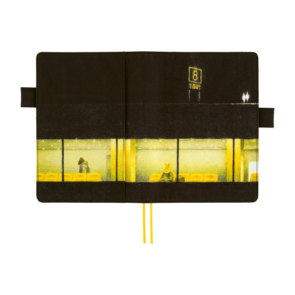 A black planner cover, featuring a printed graphic of a yellow-lit airport interior with window panes and a small yellow sign. Two yellow ribbon bookmarks extend from the bottom center.