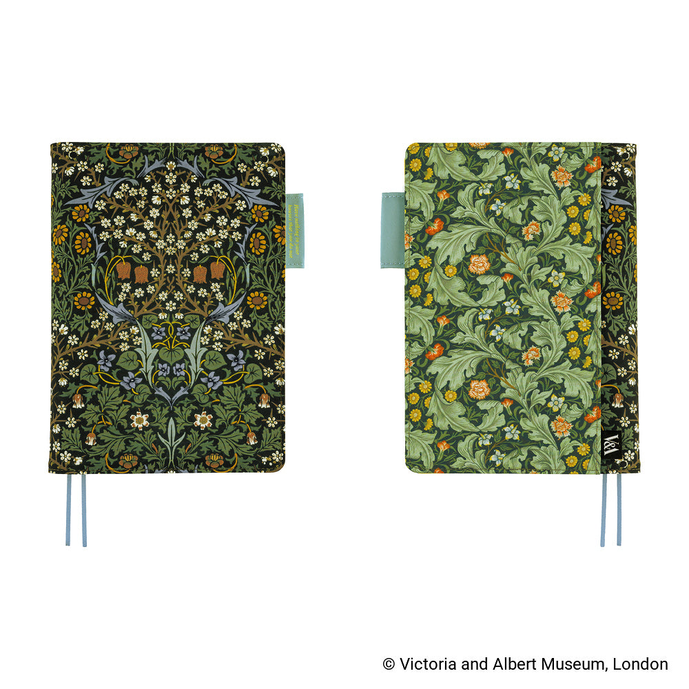 The front and back of a Hobonichi Techo cover shown side by side on a white background. The left notebook has a dark green and black pattern with white flowers and small orange accents, and the right notebook has a lighter green pattern with orange flowers and yellow details.
