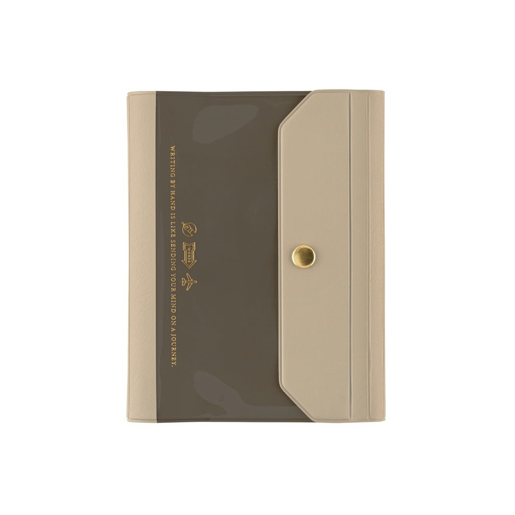 A slim A6 rectangular notebook cover with a dark taupe-brown front panel and a beige flap closure, featuring a small gold snap button and gold printed text on the left side, shown on a plain white background.