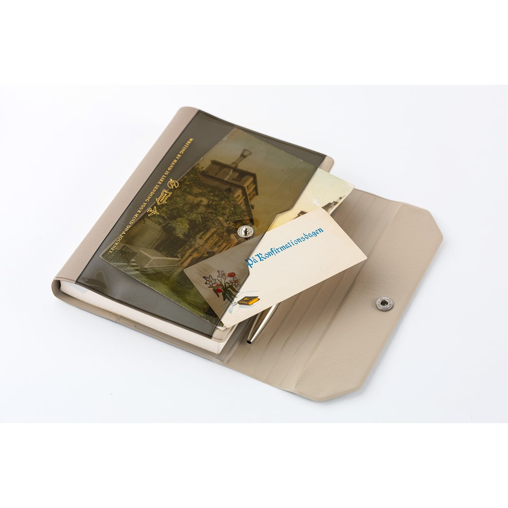 A beige and brown notebook cover shown open on a white background, with a printed card partially inserted.