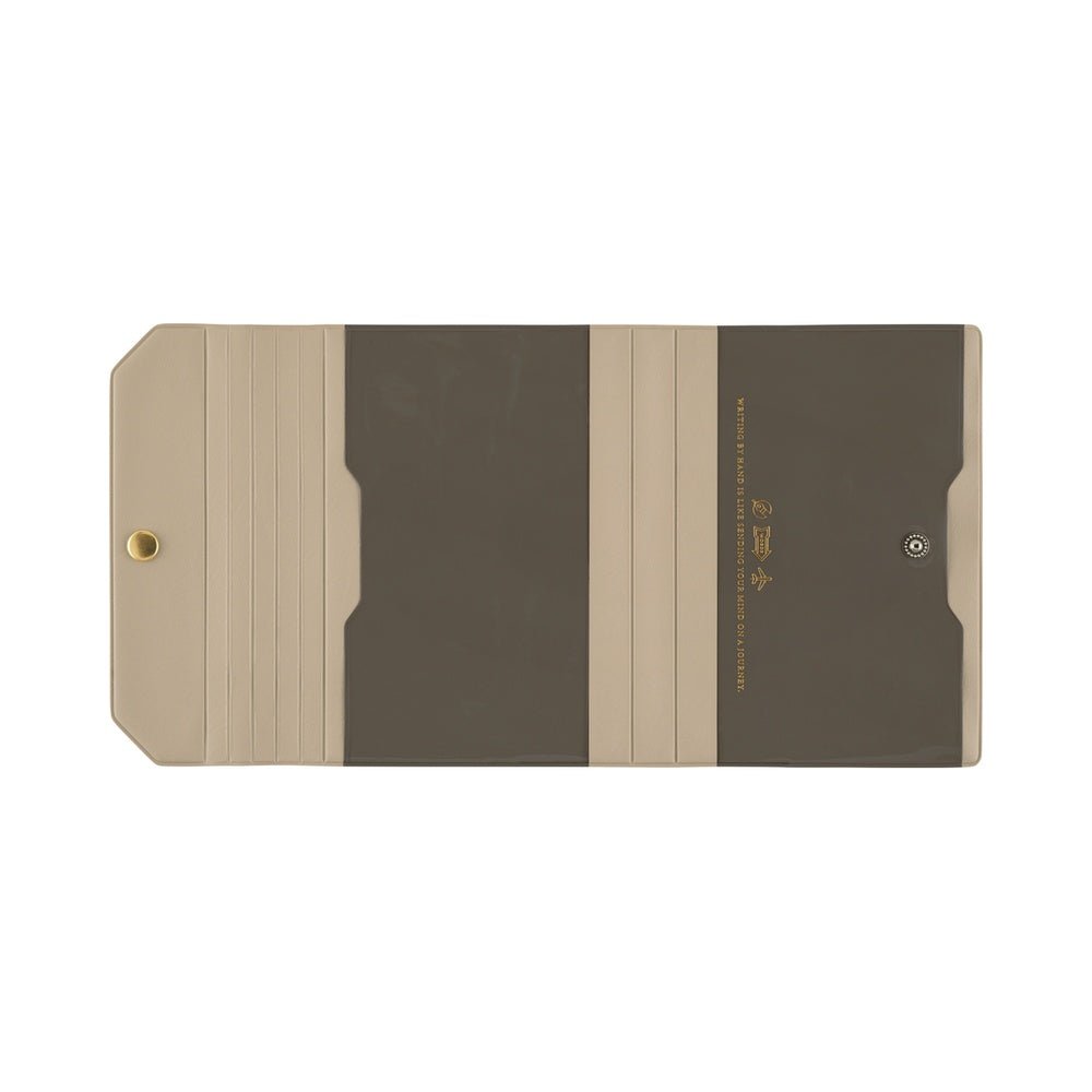 A minimalist notebook cover with in beige with dark brown sheer pockets, featuring a gold rivet on the left and gold text on the right, shown against a plain white background.
