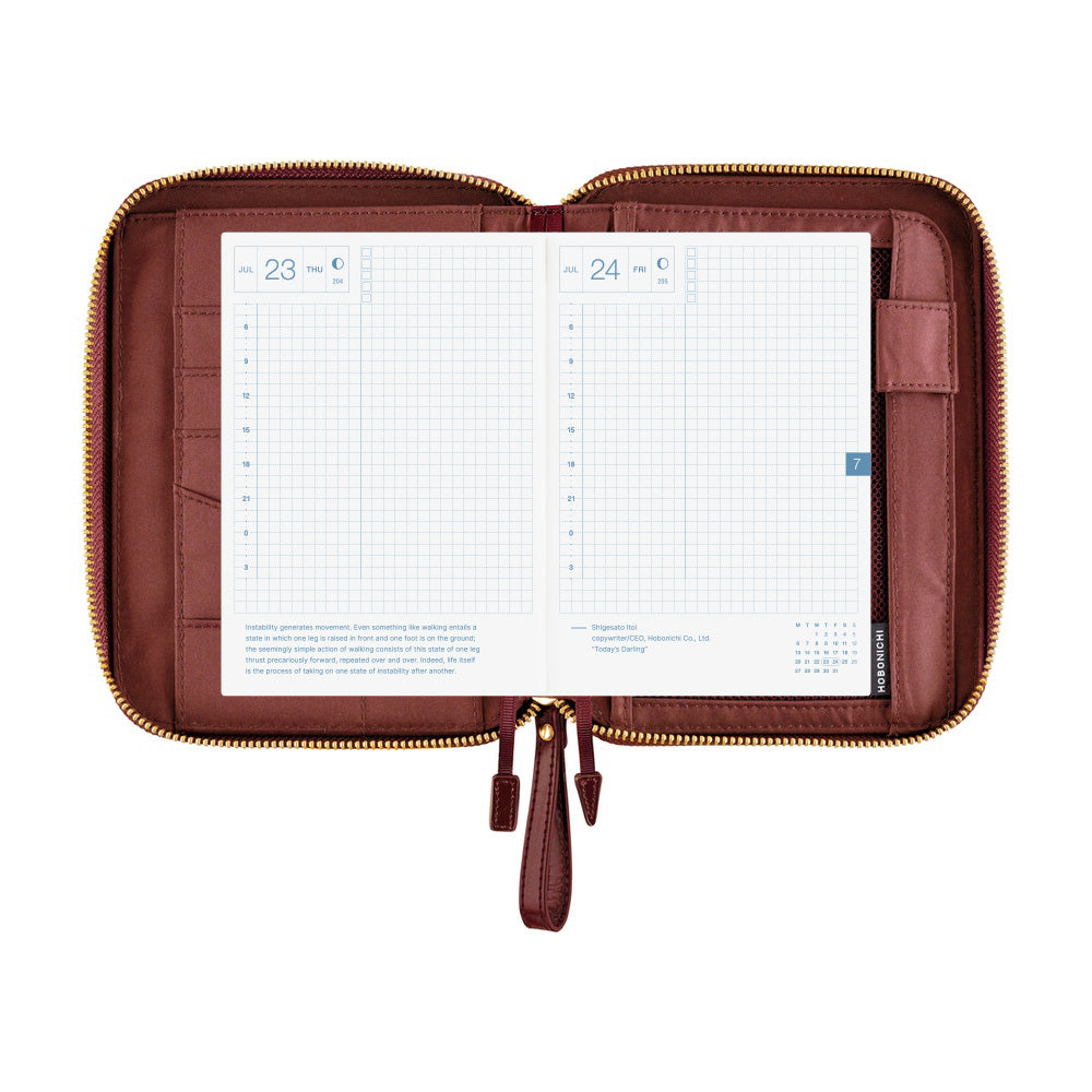 An open brown leather planner or organizer pouch with gold-tone zippers, displaying two white grid calendar inserts on a plain white background.