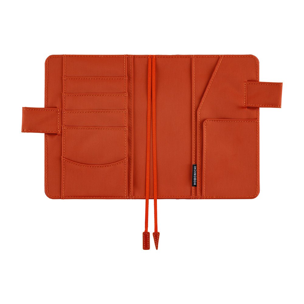 An orange-brown notebook cover shown open, featuring multiple card slots, a pocket, and bookmarks, photographed on a solid white background.