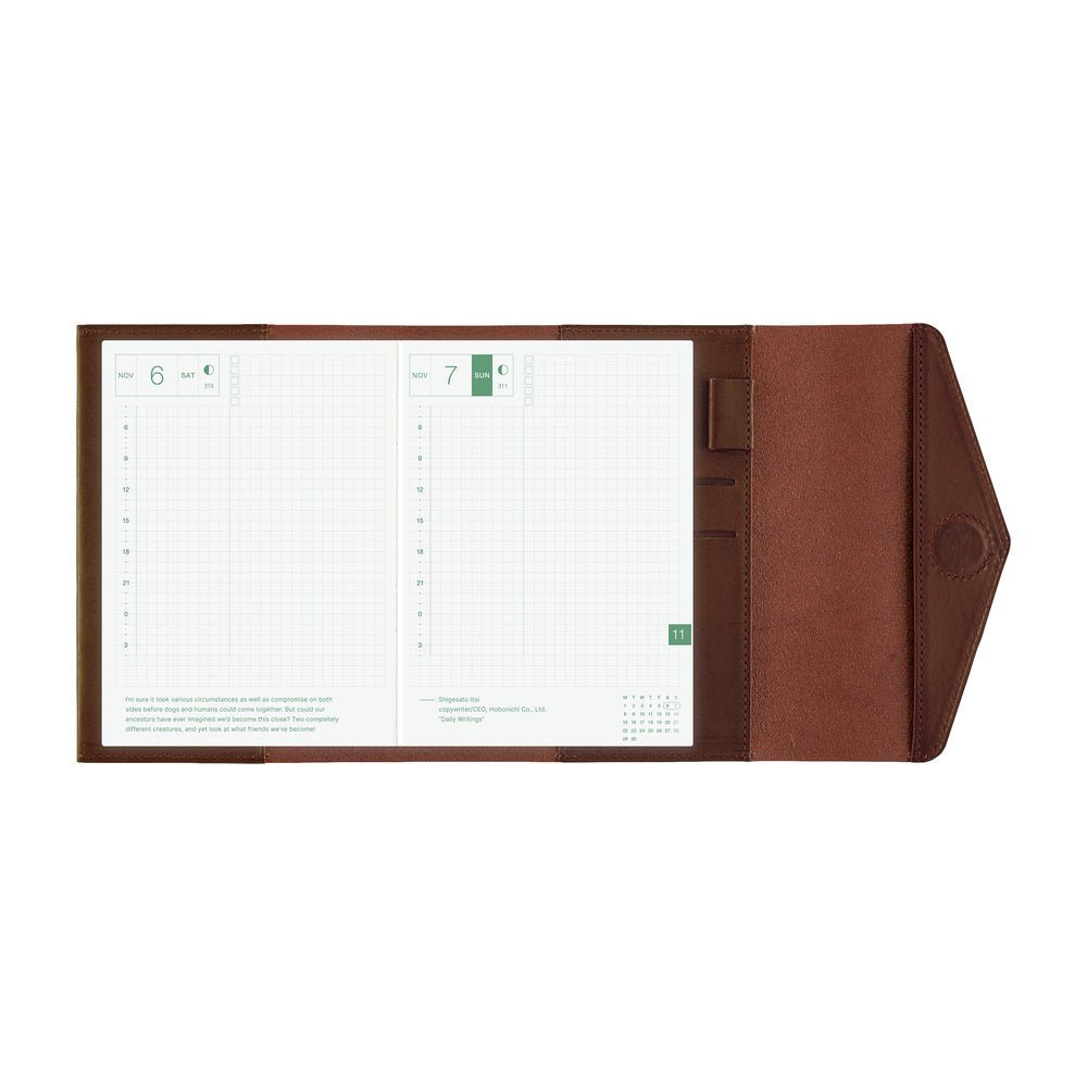 A brown leather planner cover shown open, displaying two white grid planner pages with green accents on a plain white background.
