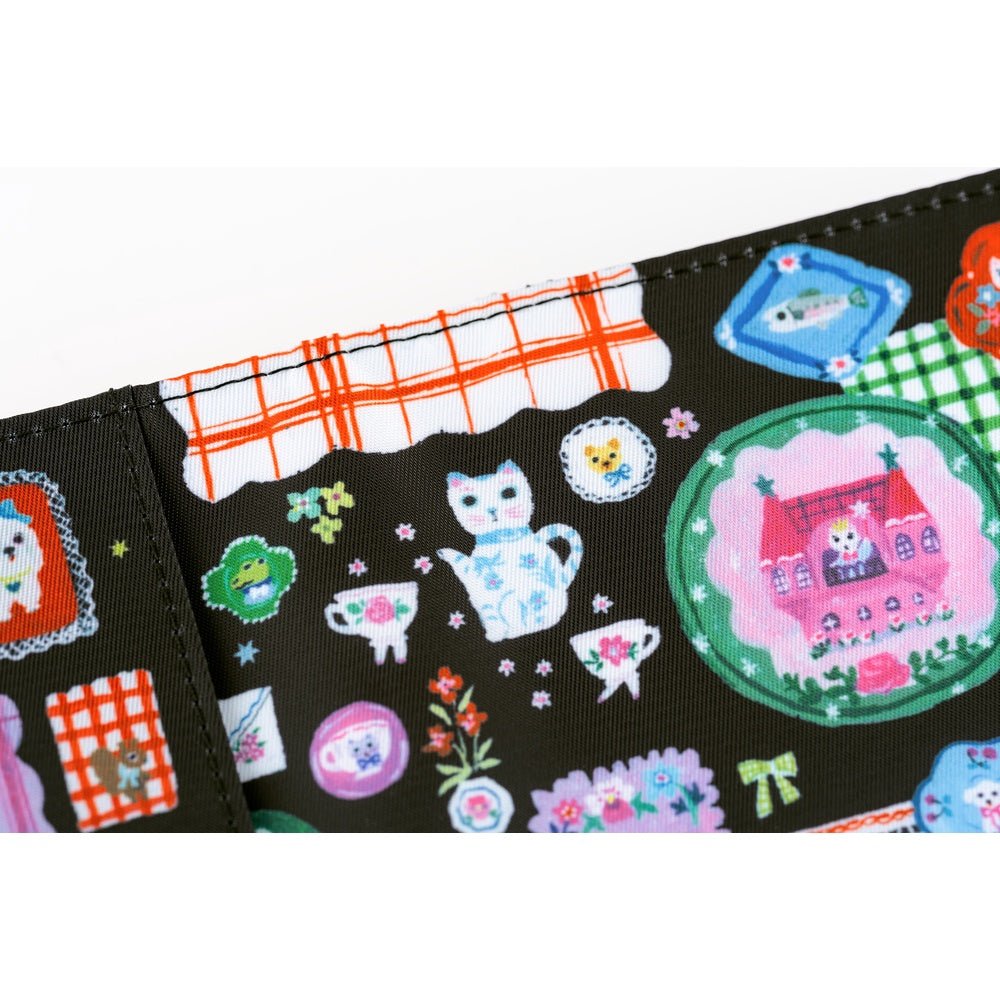 Hobonichi A6 planner cover featuring Yumi Kitagishi’s whimsical “White Cat’s Table Decorations” artwork, with a white cat-shaped teapot, teacup, colorful flowers, ribbon-tied napkin, and other cheerful tableware illustrations.