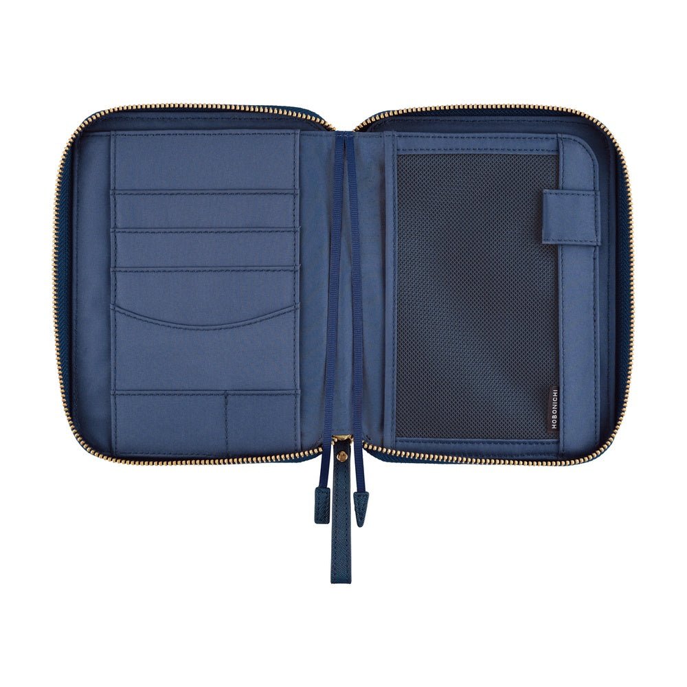 An open navy blue notebook organizer pouch with gold-tone zippers, showing interior card slots, a mesh pocket, and a small side tag on a plain white background.