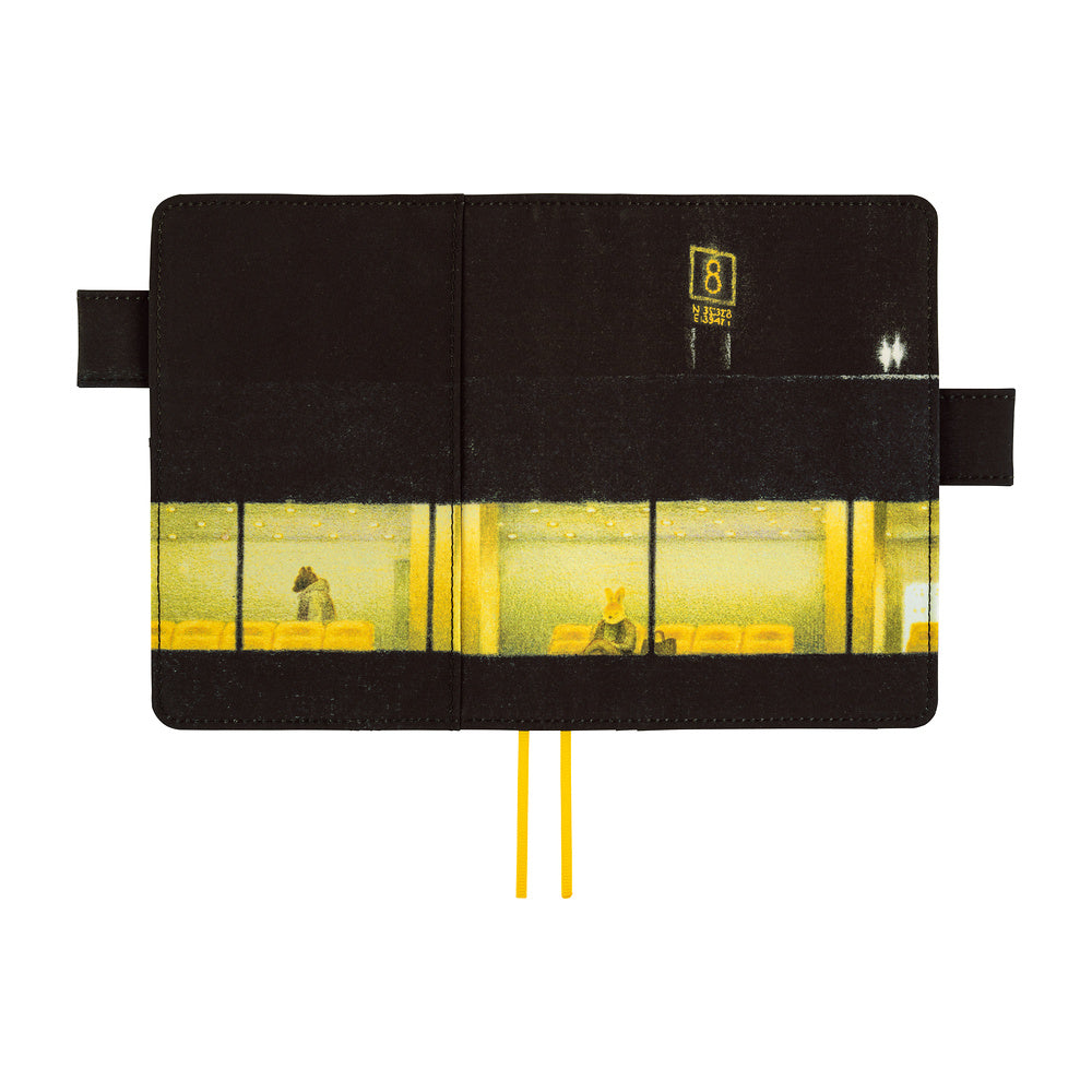 A black notebook with a printed illustration of a yellow-lit building exterior and interior, shown open against a white background. Two yellow ribbon bookmarks extend from the bottom.