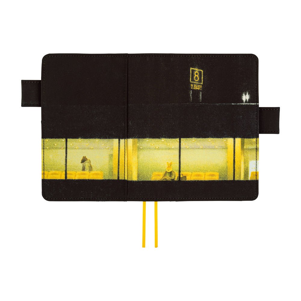 A black notebook with a printed illustration of a yellow-lit building exterior and interior, shown open against a white background. Two yellow ribbon bookmarks extend from the bottom.