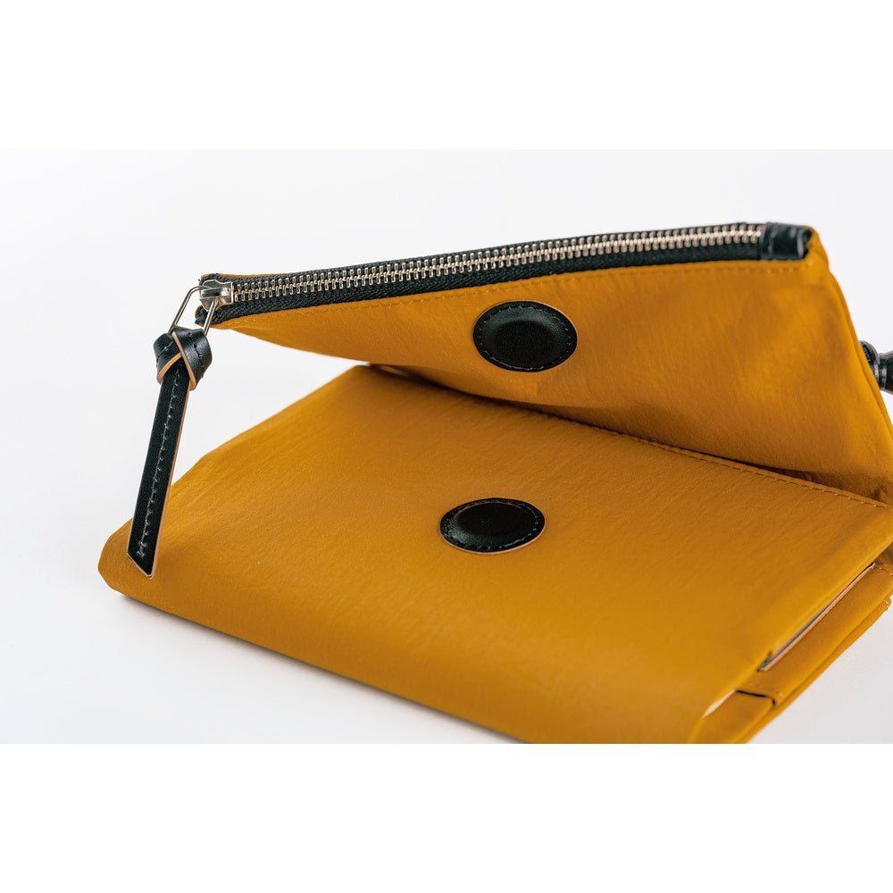 Mustard notebook with a black strap on a white background