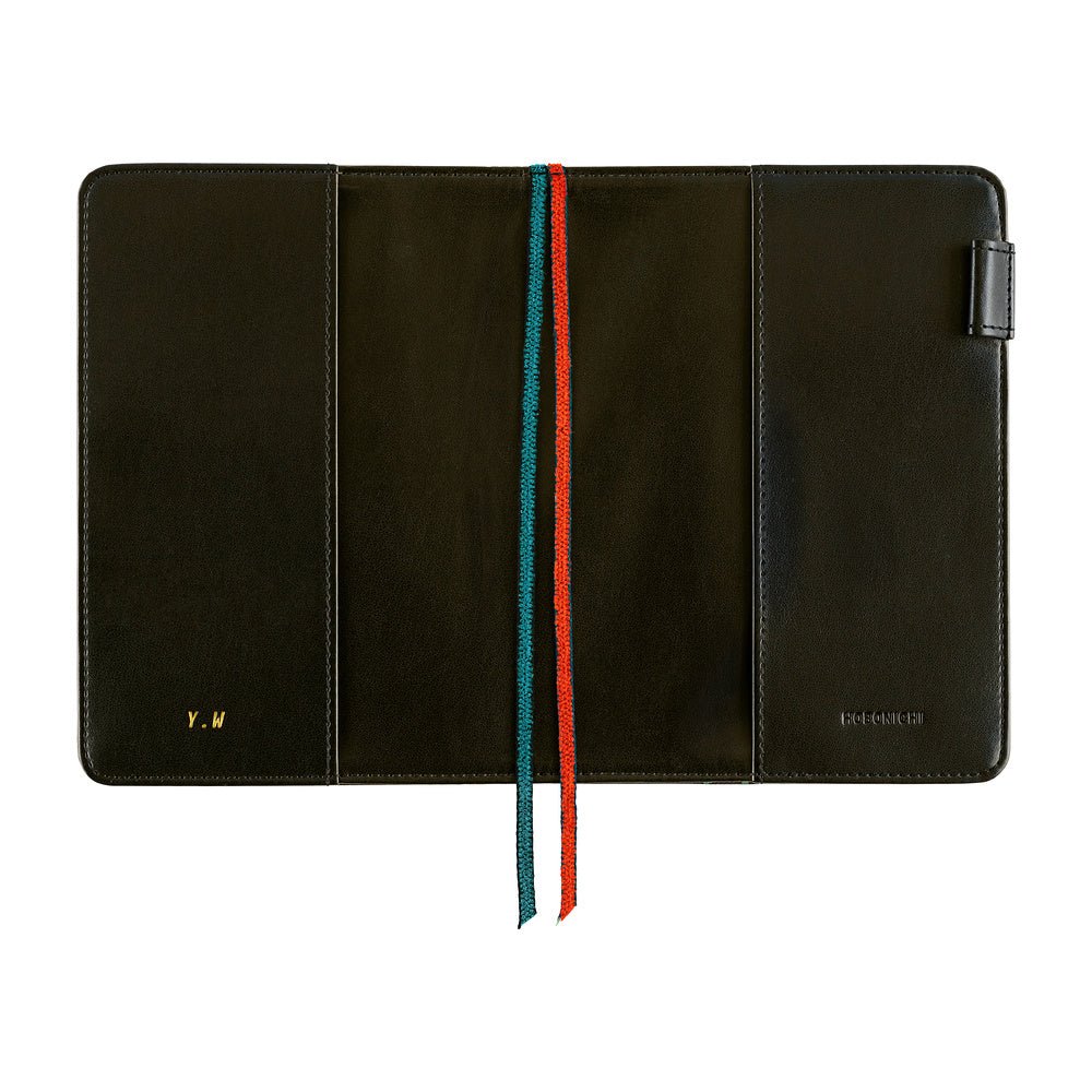 A black folio-style notebook cover shown open against a white background, with a vertical two-colored ribbon bookmark in teal and orange running down the center. Small gold branding text is visible near the bottom corners.