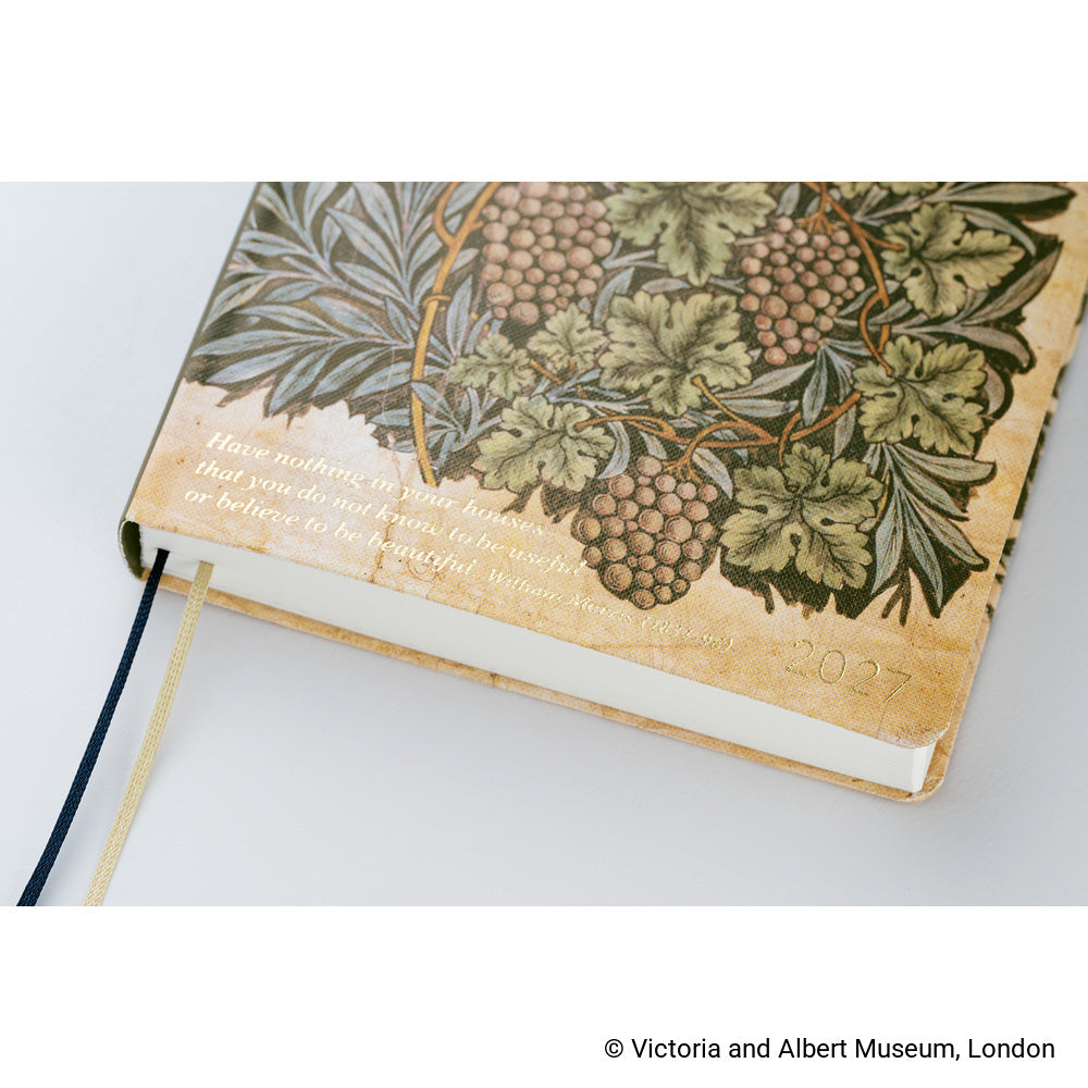 Close up of a 2027 Hobonichi Techo HON hardcover planner featuring the V&A Vine botanical design with clusters of grapes and dense foliage, and a quote reading, 'Have nothing in your houses that you do not know to be useful or believe to be beautiful.'