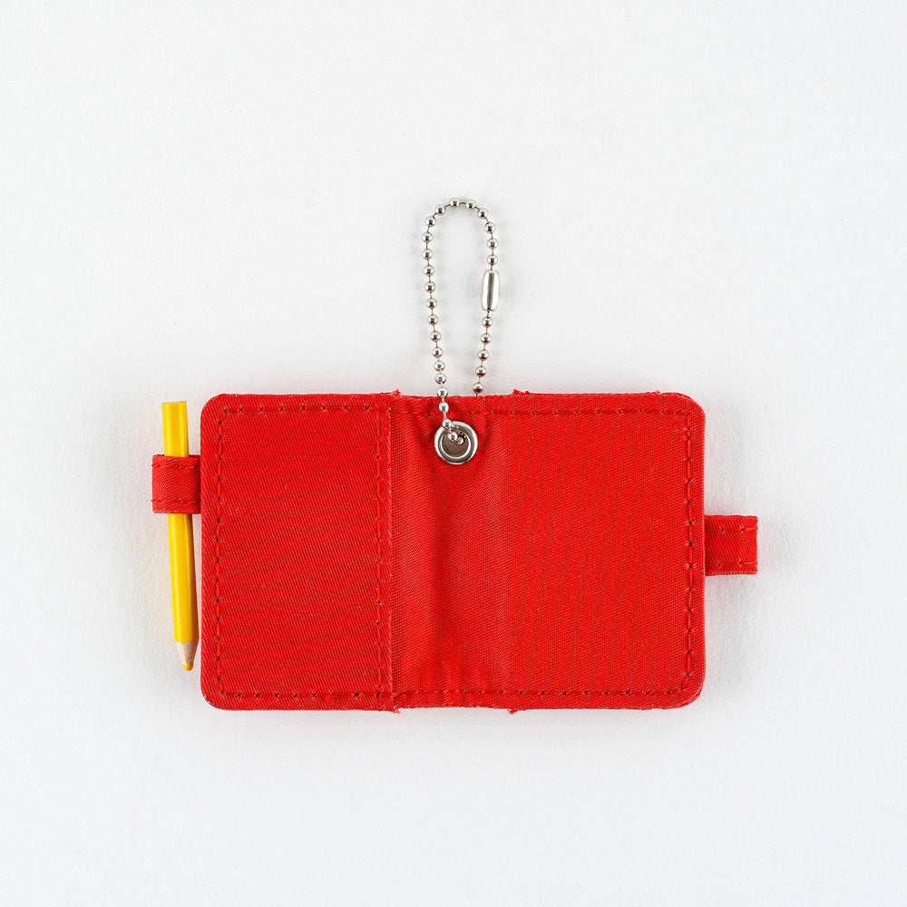 Open small red notebook keychain with a silver ball chain and a red loop holding a yellow pencil shown on a plain white background.