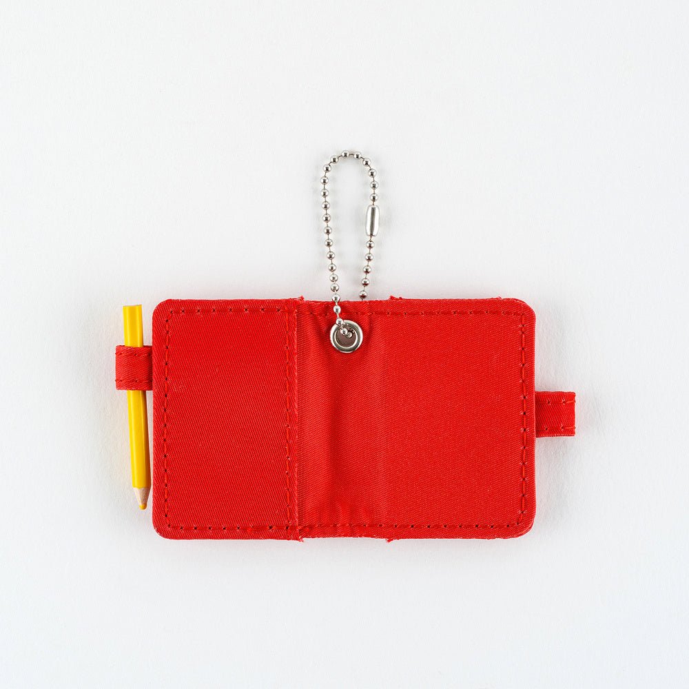 Open small red notebook keychain with a silver ball chain and a red loop holding a yellow pencil shown on a plain white background.