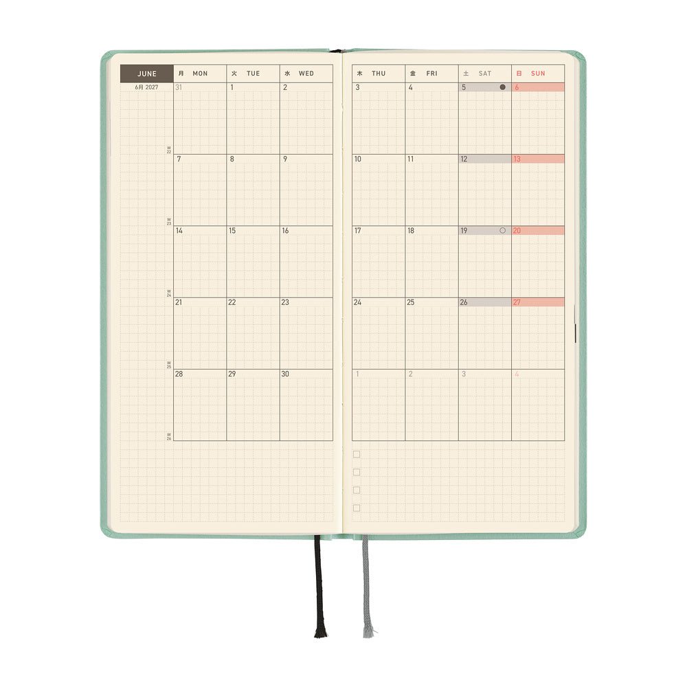 An open planner showing a monthly spread with grid pages, a mint green cover, and ribbon bookmarks, shown on a plain white background.