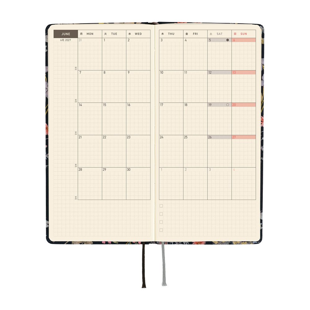 An open planner showing a monthly calendar spread on cream grid pages.