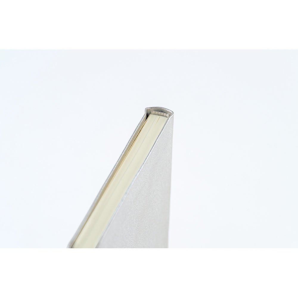 A close-up shot of the binding of a planner book with a silver leather cover and cream colored pages.
